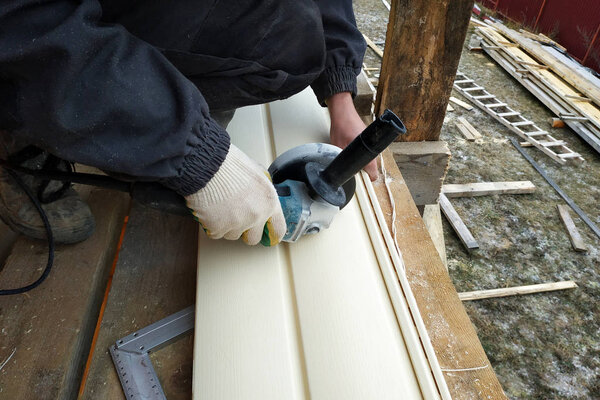 An employee cuts siding to the required size 2019