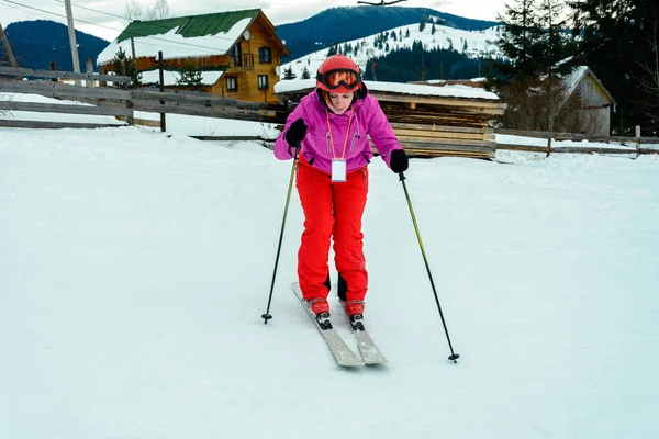 Eine schöne Frau in roter Kleidung lernt Skifahren in den ukrainischen Karpaten — Stockfoto