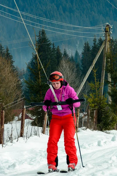 Eine junge Frau in rotem Gewand hebt einen Skilift auf einen Berg in den Karpaten — Stockfoto