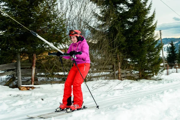 赤いギアで若い女性はカルパティア山脈の山の上にスキー場のリフトを発生させます — ストック写真