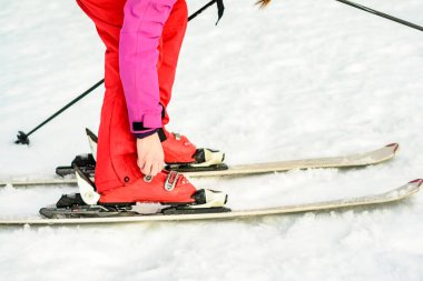 Woman in red-pink clothes wearing ski footwear for skiing clipart