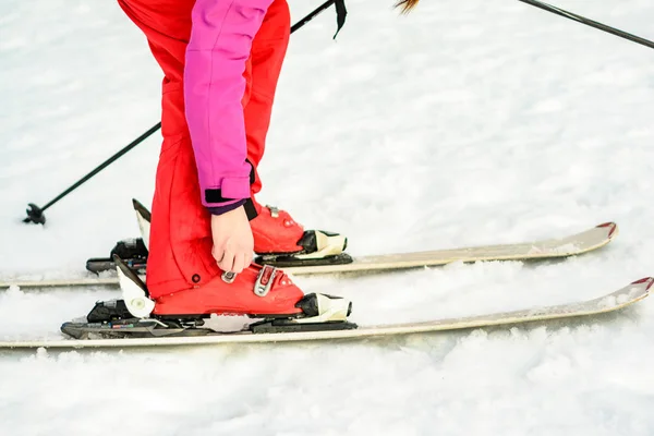 Frau in rot-pinkfarbener Kleidung mit Skischuhen zum Skifahren — Stockfoto