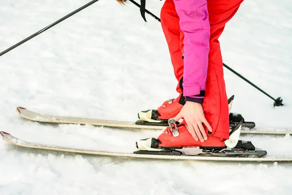 Frau in rot-pinkfarbener Kleidung mit Skischuhen zum Skifahren — Stockfoto