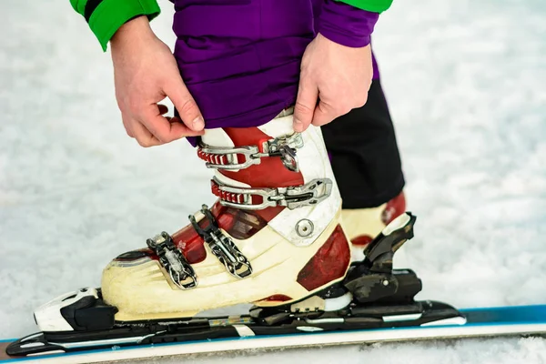 スキーヤーはスキーの靴を身に着けているし、ファスナーを修正 — ストック写真