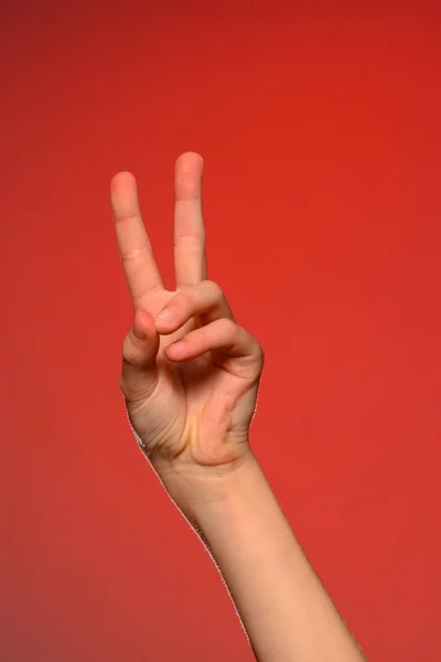 La mano suave que muestra la señal de victoria está aislada en una espalda roja — Foto de Stock