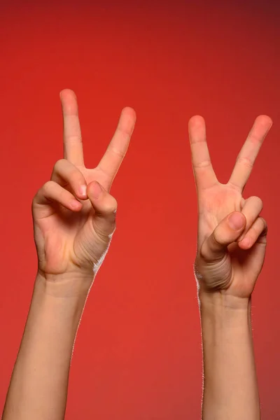 Two beautiful hands showing a victory sign isolated on a green background — Stock Photo, Image