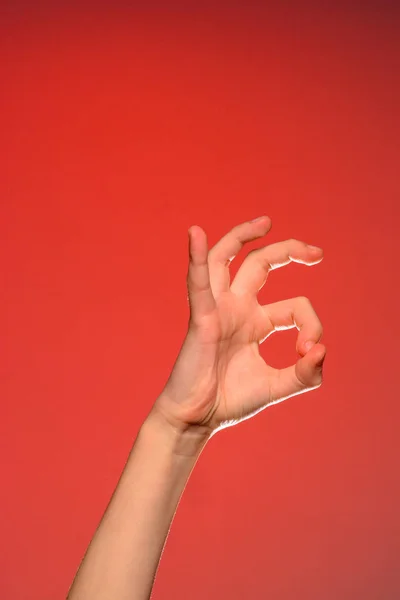 La mano humana muestra el signo ok que simboliza lo positivo, aislado sobre un fondo rojo . — Foto de Stock