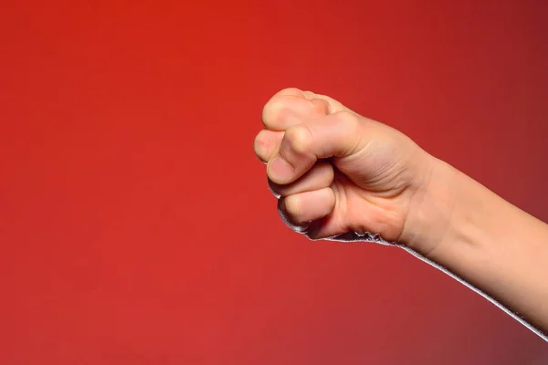 Mano humana que apretó los dedos en un puño, simbolizando el odio y la resistencia, aislada sobre un fondo rojo — Foto de Stock