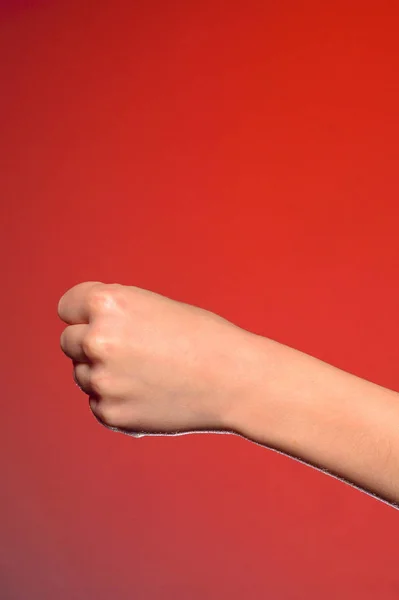 मानव हाथ जिसने एक मुट्ठी में उंगलियों को चिपकाया, घृणा और प्रतिरोध का प्रतीक, एक लाल पृष्ठभूमि पर अलग — स्टॉक फ़ोटो, इमेज