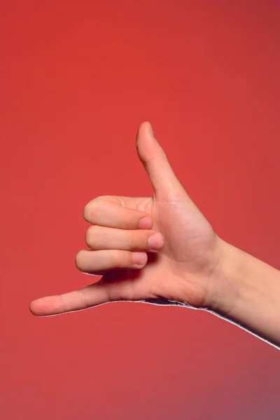 Tecken på ett telefonsamtal visar en hand isolerad på en röd bakgrund — Stockfoto