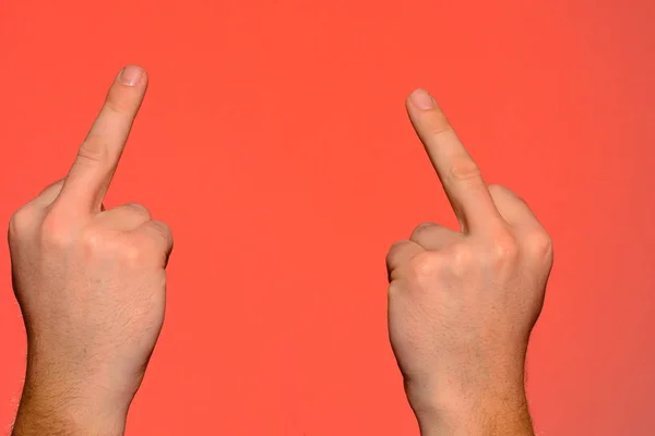 Mano humana mostrando un gesto obsceno con un dedo medio aislado sobre un fondo rojo . — Foto de Stock