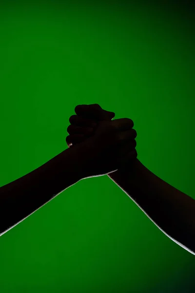 Дві руки рукостискають, ізольовані на зеленому тлі, символізуючи дружбу і примирення — стокове фото