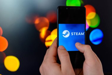 Los Angeles, Kaliforniya, ABD - 9 Mart 2019: adam tutar ile renkli bir bulanık yan ve arka plan üzerinde buhar firma logosu ile akıllı telefon yakın çekim