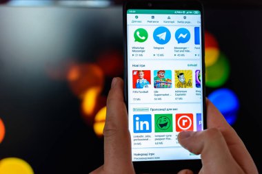 Lviv, Ukrayna - 09 Mart 2019: Adam akıllı telefon onun elleri yakın çekim tutar ve bulanık bir arka plan üzerinde Google oyun için belgili tanımlık kullanma açık