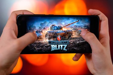 Los Angeles, Kaliforniya, ABD - 9 Mart 2019: adam akıllı telefon yakın çekim elinde tutar ve renkli bir bulanık yan arka plan karşı dünyanın tankları Blitz çalış.
