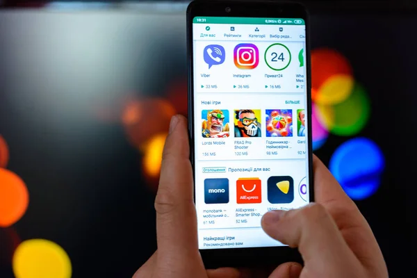Lviv, Ukrayna - 09 Mart 2019: Adam akıllı telefon onun elleri yakın çekim tutar ve bulanık bir arka plan üzerinde Google oyun için belgili tanımlık kullanma açık