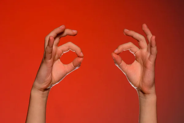 Dos manos humanas muestran un signo ok, aislado sobre un fondo rojo — Foto de Stock