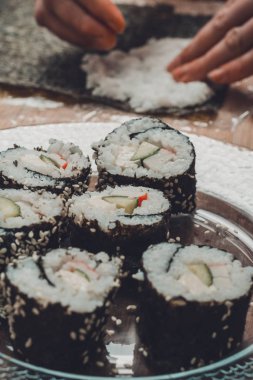 Kendi elleri ile bir kadının Şef tarafından pişirilmiş suşi rolleri mutfakta bir tabak