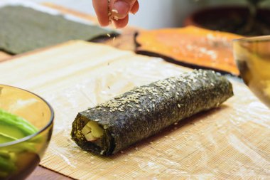 Kadınların elleri yakın bir restoran serpin susam yağı sushi hazırlanması sırasında