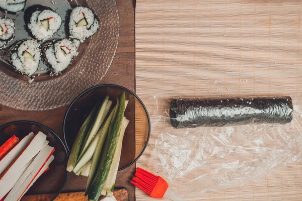 Homemade sushi. Male hands prepare rolls with rice, salmon, crab, cheese, nori, cucumber — Stock Photo, Image