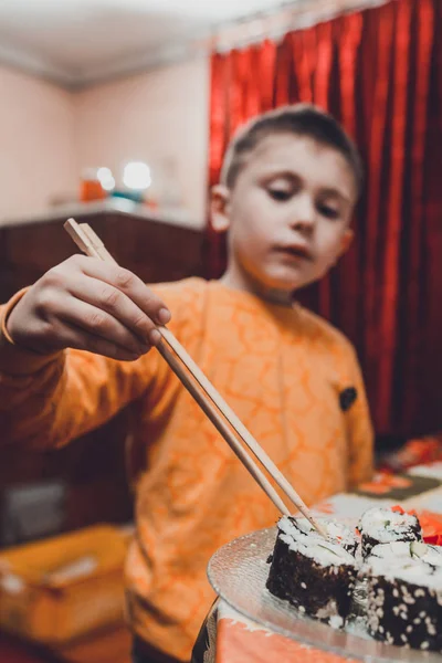 Der Teenager nimmt die Sushi-Rolle vom Teller zum Essen — Stockfoto