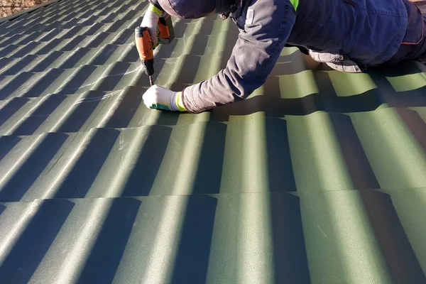 Profesionální pracovník pracuje na instalaci střešní střechu listy kovové dlaždice a vrtačky šroubem s vrtačkou — Stock fotografie