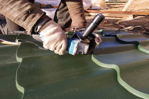 O mestre corta uma folha de metal profissional para instalação no telhado da casa — Fotografia de Stock