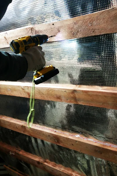 Sihirbaz Akülü matkap kullanır ve sabitleyen vidayı folyo film ve mineral yün Evin çatısı iyileşmek için tutun panoları vida — Stok fotoğraf