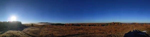 Atemberaubendes Panorama der ländlichen Herbstlandschaft eines europäischen Dorfes mit einem farbenfrohen Himmel und einem unendlichen goldenen Feld. — Stockfoto