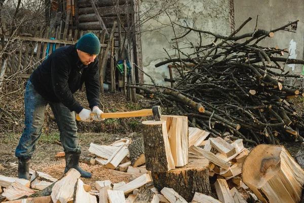 Сильний чоловік збирає дрова на зиму на задньому подвір'ї будинку, вирізаючи велику і міцну траву — стокове фото