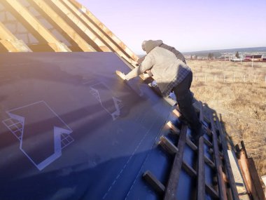 Evin çatısı işçilerin çatısı altında su geçirmez bir film yüklemek ve bir zımba ile güvenli