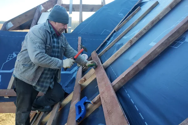 The master clogs the nail into a beam, fixing this gidrorizer to the rafters