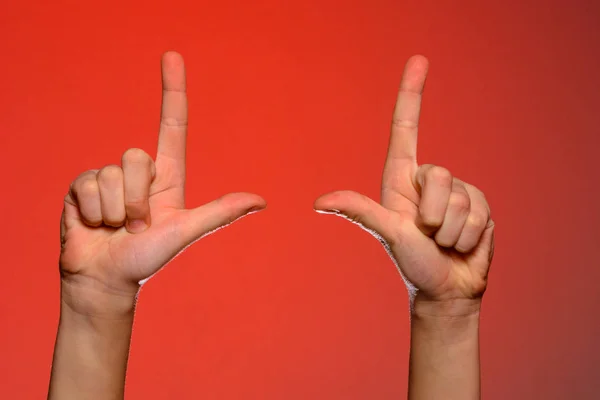 Mano humana con los dedos doblados, muestra un dedo índice que simboliza una pistola, aislada sobre un fondo rojo — Foto de Stock