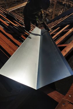 Usta bir metalik levha çatı yağmur sırasında drenaj için kırılma noktasında yükseltir