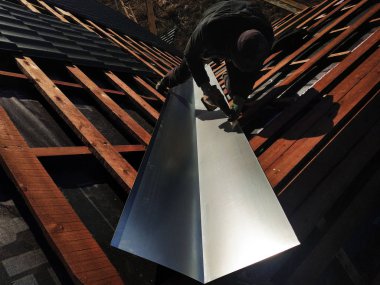 Usta bir metalik levha çatı yağmur sırasında drenaj için kırılma noktasında yükseltir