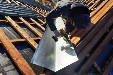 Usta bir metalik levha çatı yağmur sırasında drenaj için kırılma noktasında yükseltir