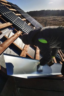 Usta bir metalik levha çatı yağmur sırasında drenaj için kırılma noktasında yükseltir