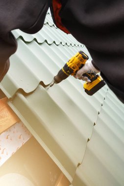 Profesyonel çalışan bir metal kiremit yaprak tarafından bir çatı çatı yüklemesinde çalışır ve bir vida bir matkapla matkaplar