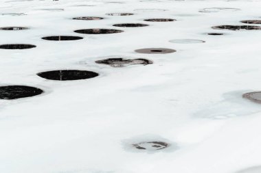 Buz kaplı göl, doku ve arka planda çok sayıda delik, delik ve delik.