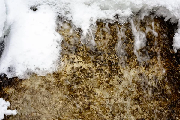 Uma pequena cachoeira coberta de neve em algum lugar distante na floresta montanhosa . — Fotografia de Stock