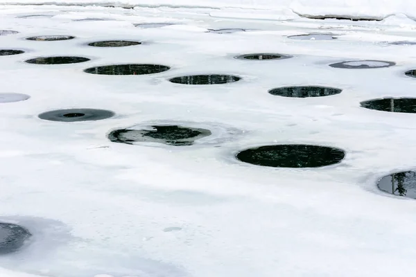 A large number of holes, holes and holes on the ice-covered lake, texture and background.