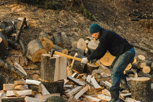 Сильный мужчина заготавливает дрова на зиму на заднем дворе дома, вырубая большую и красивую траву — стоковое фото