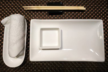 Beyaz seramik kaseler ve beyaz havluyla suşiden bambu çubukları..