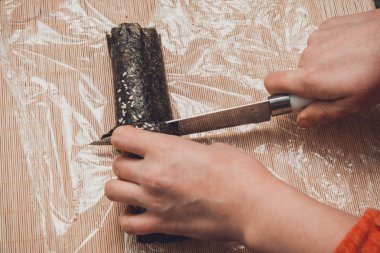 Bir kadın mutfakta bir rulo suşi bıçakla adet düzeyinde ziyaretçiler için keser