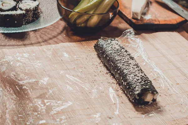 Homemade sushi. Male hands prepare rolls with rice, salmon, crab, cheese, nori, cucumber — Stock Photo, Image