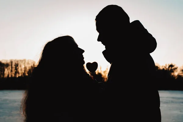 Silhouette eines schönen Paares vor dem Hintergrund des Sees und des Abendhimmels im Park. — Stockfoto