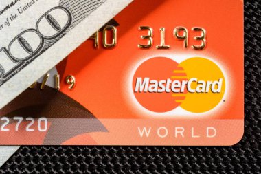Lviv, Ukrayna - 26 Nisan 2019 : Mastercard logolu kırmızı kart, yüz dolarlık banner yakın çekime yerleştirilir.