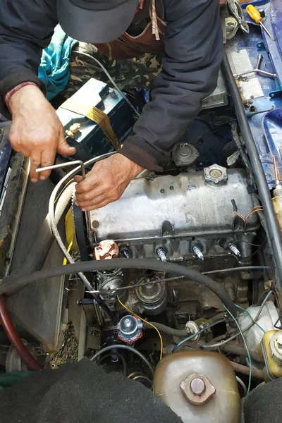 Mechanik samochodowy odblokowuje pokrywę silnika starego samochodu i naprawi go. — Zdjęcie stockowe