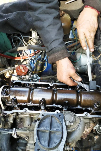 O mestre na garagem bate as válvulas no carro velho, carro VAZ, um carro velho desgastado . — Fotografia de Stock