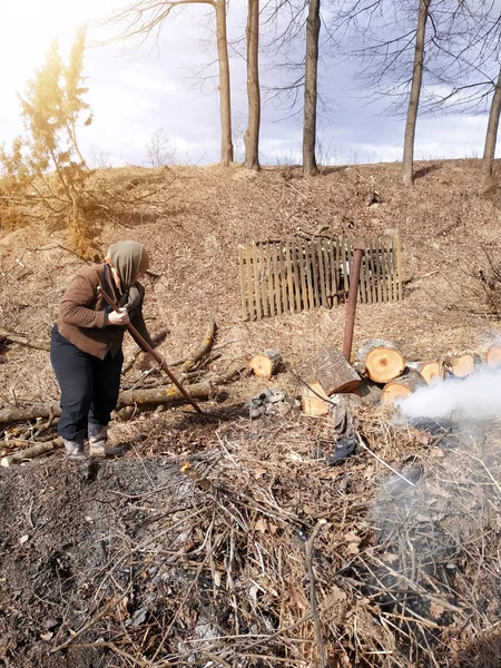 Літня жінка очищає двір біля свого будинку після вирубки деревини на дровах . — стокове фото
